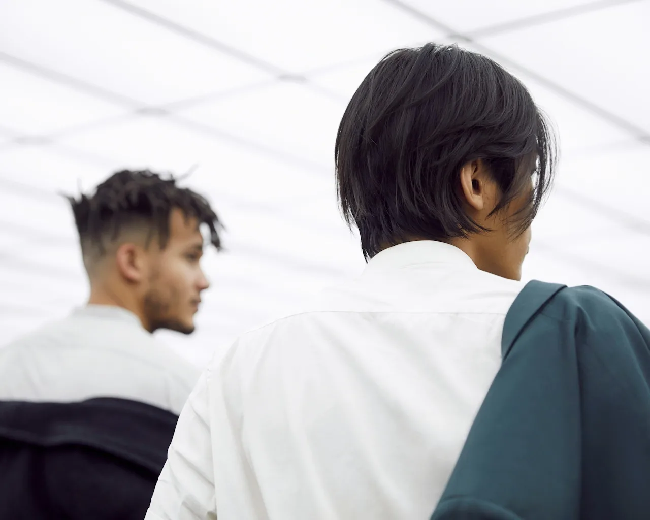 Back view of two young men with dark hair in a bright open space