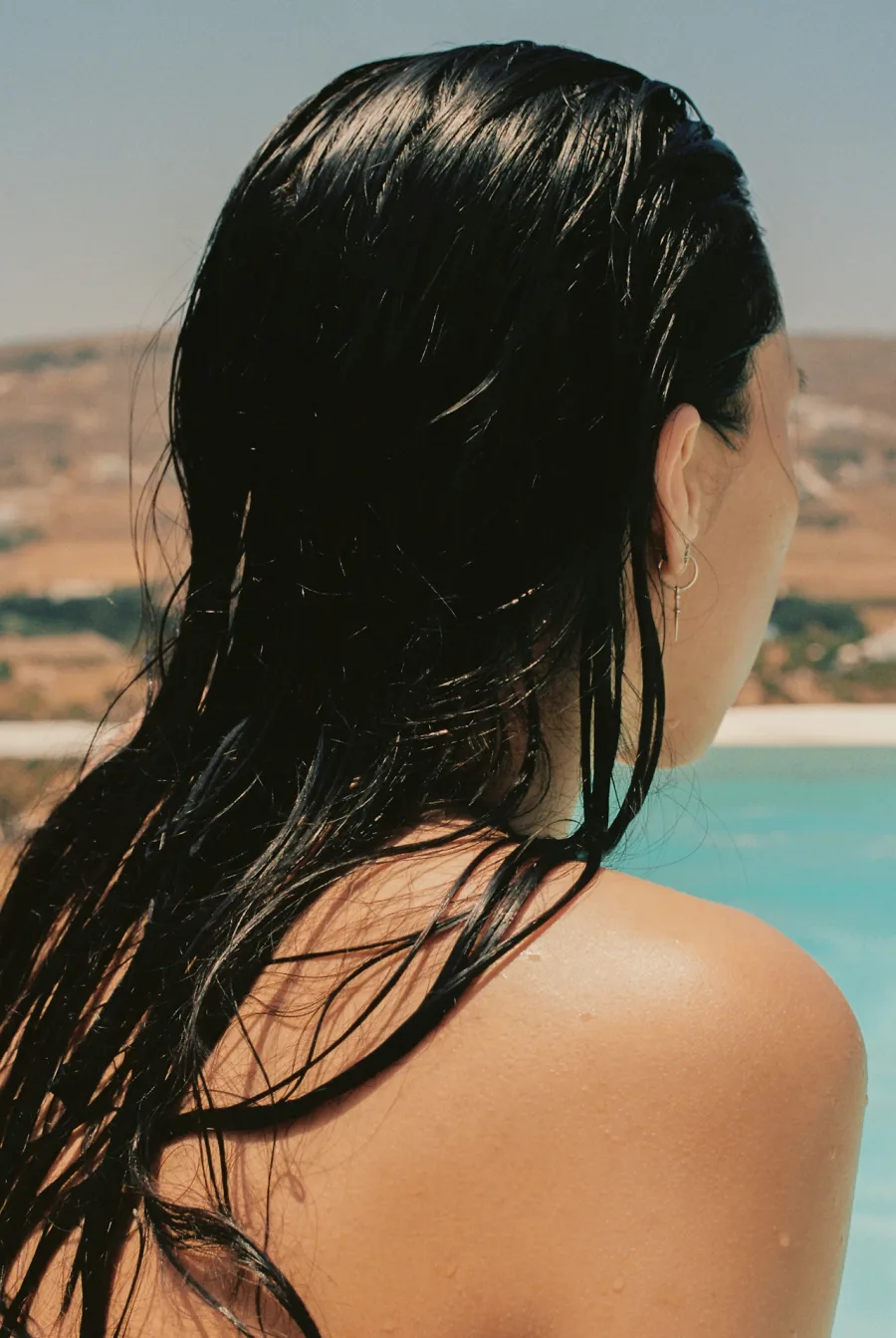 Woman with long dark wet hair looking out over a sunlit landscape