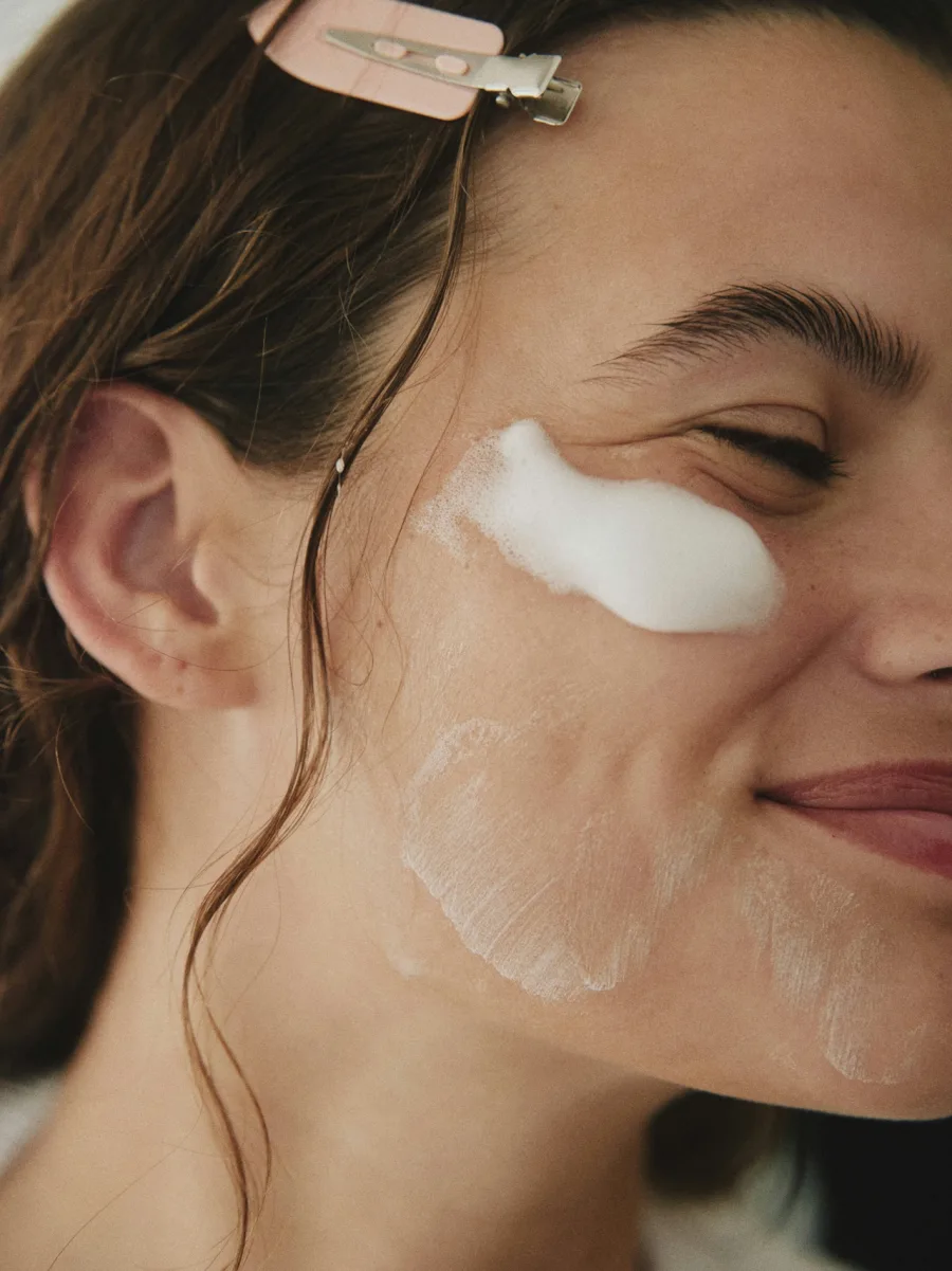 Close-up of a woman smiling with skincare product on her cheek